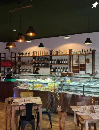 El mostrador de la fiambrería con quesos, vinos en los estantes y mesas de madera
