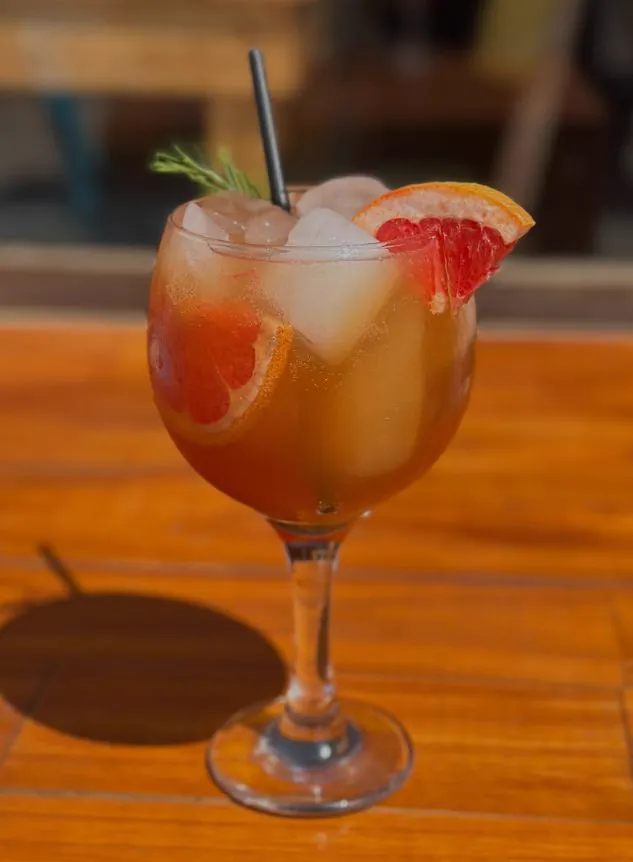 Trago con pomelo y romero sobre una mesa de madera al sol